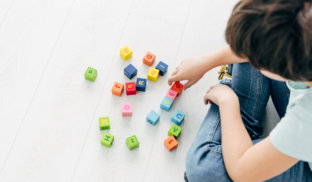 cropped view of kid with dyslexia playing with colorful building blocks